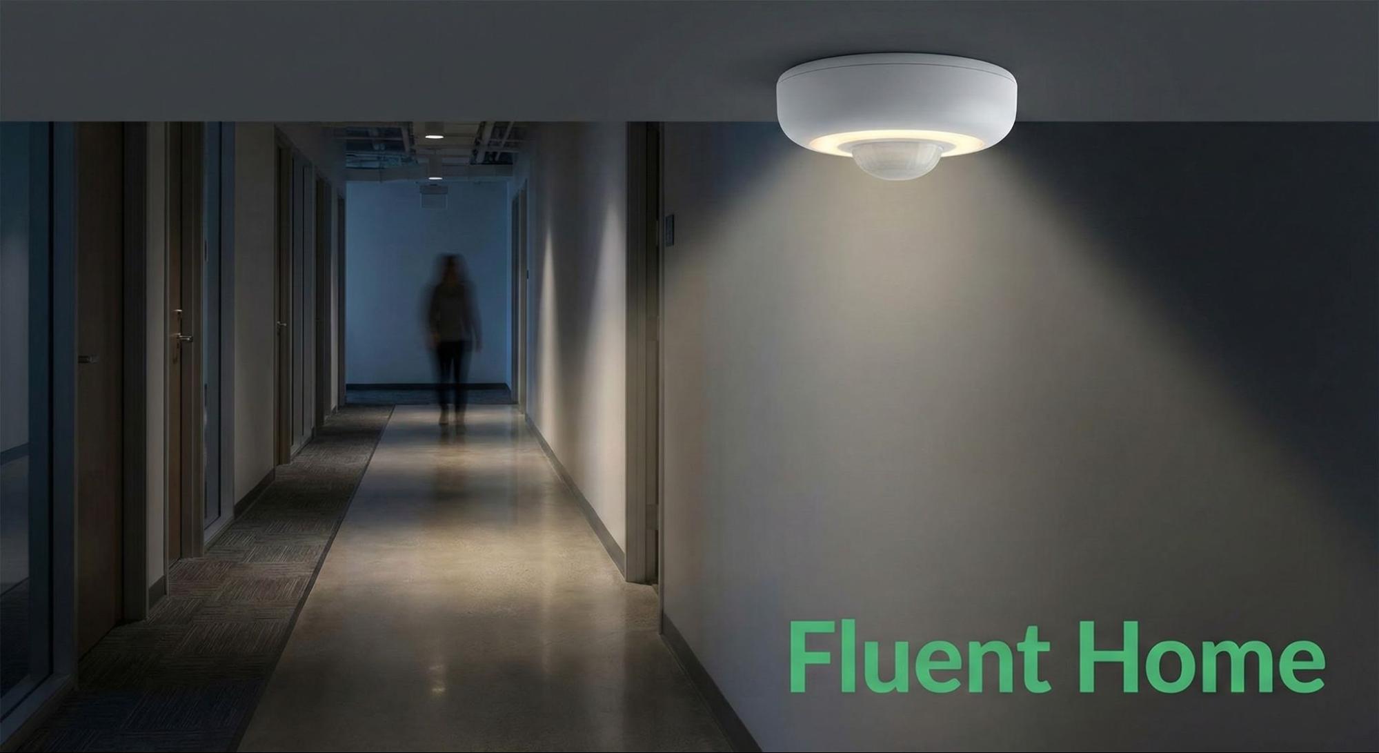 Ceiling-mounted motion sensor illuminating a dim hallway as a person walks toward the camera.